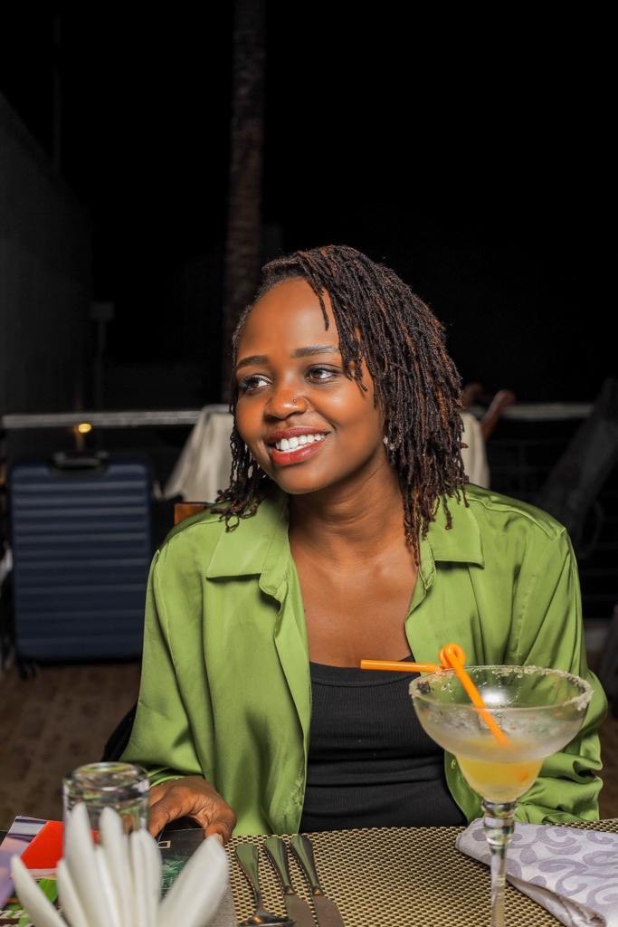 Lorna Maina smiling in a red plaid shirt and tortoise shell glasses